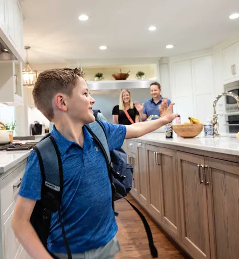 Boy with backpack in kitchen