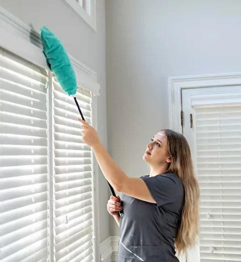 Merry Maids team member dusting window