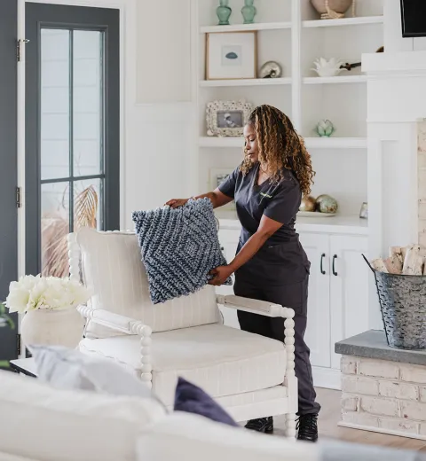 Cleaner fluffing pillows in living room