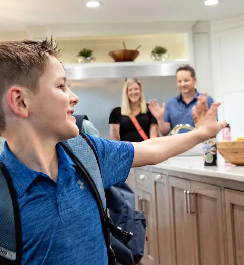 Boy waving to family in kitchen