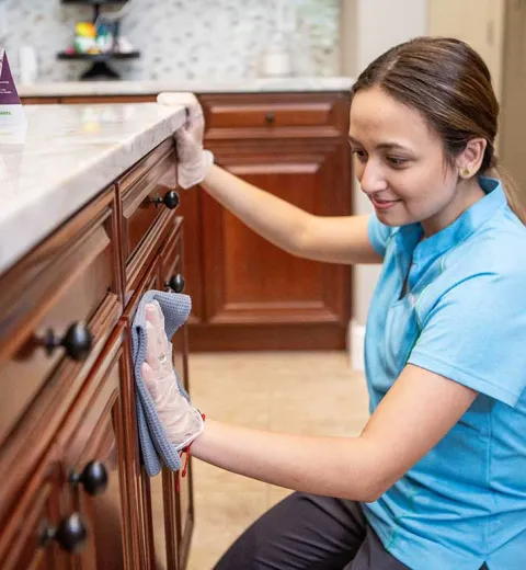 Merry Maids team member wiping cabinets