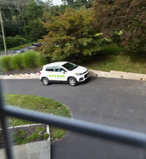 merry maids branded vehicle parked on the road outside of a window