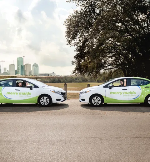 merry maids in branded vehicles in front of the houston skyline