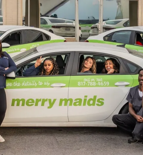merry maids posing by branded vehicles