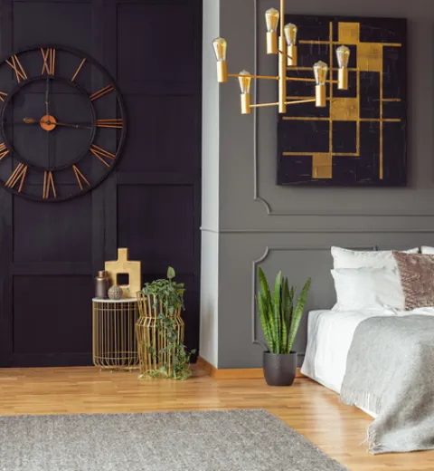Dark bedroom interior with fresh plants, carpet on floors, double bed, and gold lamp | Merry Maids