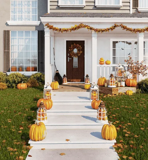 House decorated for Halloween with fall leaves in yard.