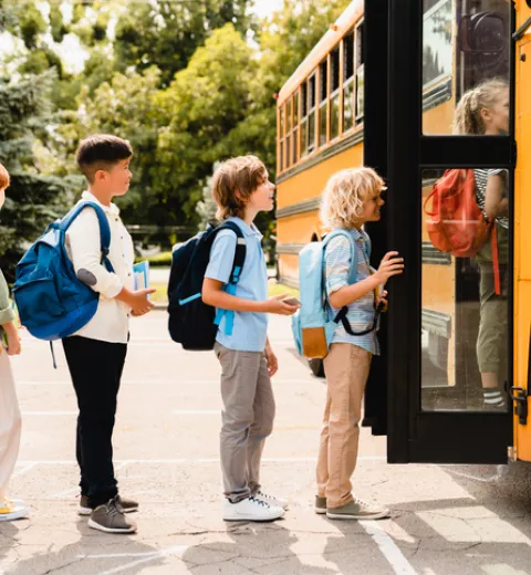 Kids waiting in line to get on a school buss | Merry Maids