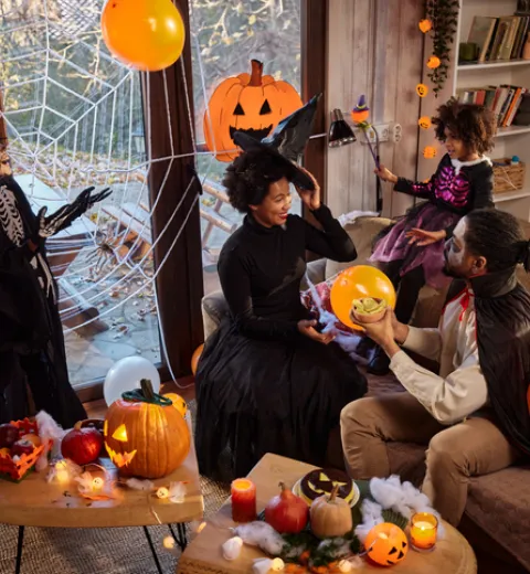 Happy African American family in costumes talking during a Halloween celebration at home | Merry Maids