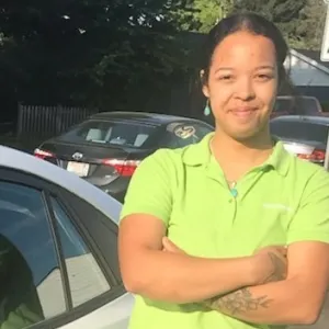 faith is leaning against a merry maids car wearing a green merry maids shirt