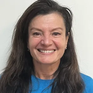 ana is standing in front of a grey wall wearing a blue merry maids tshirt