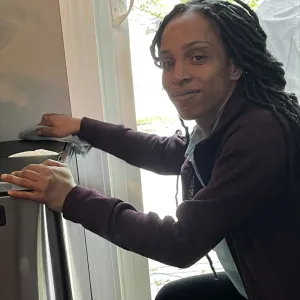 angel is dusting a dark wooden cabinet
