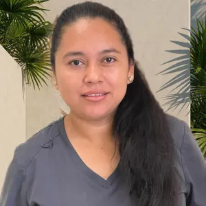 smiling woman wearing a grey merry maids uniform standing in front of a tan wall