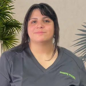 woman wearing a grey merry maids uniform standing in front of a tan wall