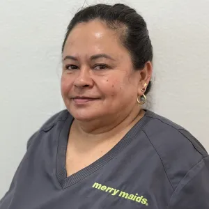 smiling woman with a grey merry maids uniform standing in front of a tan wall