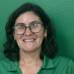 Christine is wearing a green merry maids shirt standing in front of a green wall