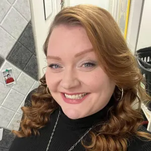 jebra is wearing a black sweater smiling at the camera