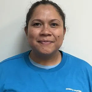 mercedes is smiling in front of a grey wall wearing a merry maids tshirt