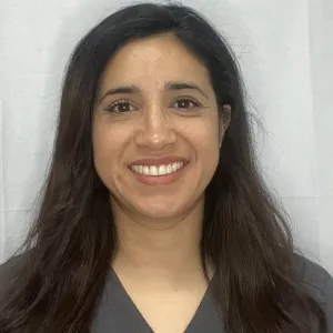 Selene is standing in front of a grey wall wearing a merry maids uniform