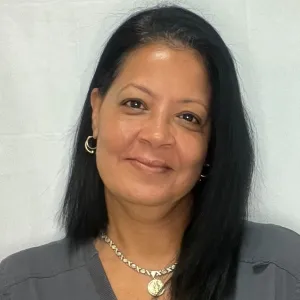 Sumi is standing in front of a grey wall wearing a merry maids uniform
