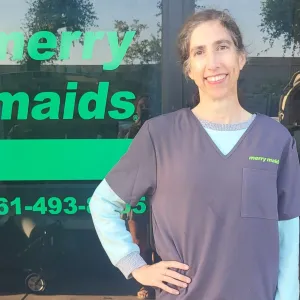 merry maids team member standing in front of a merry maids storefront 