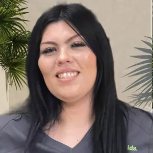 smiling woman with a grey merry maids uniform standing in front of a tan wall