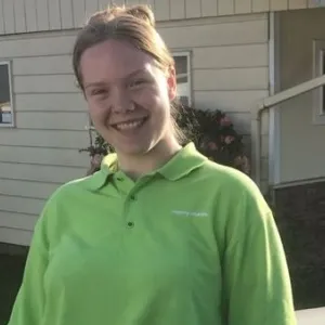 payton is leaning against a merry maids car wearing a green merry maids shirt