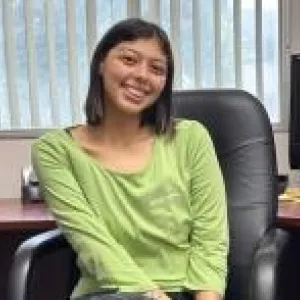 joselyn is sitting in a black leather desk chair smiling at the camera