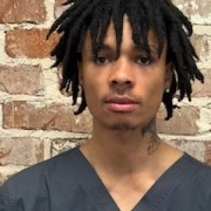 man wearing a grey merry maids uniform standing in front of a brick wall