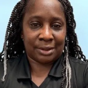 smiling woman with a grey merry maids uniform standing in front of a blue wall