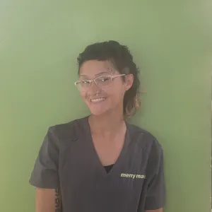 Chloe standing in front of a green wall wearing glasses