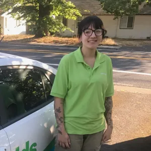 merry maid smiling besides a white branded car