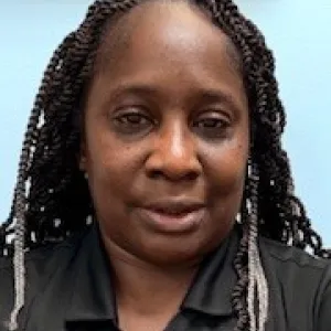 smiling woman with a grey merry maids uniform standing in front of a blue wall