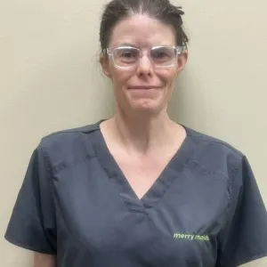 Smiling female in grey scrubs with Merry Maids logo with hair tied in the back