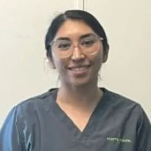 A smiling female Merry Maids ambassador with glasses in grey scrubs with dark hair pulled back