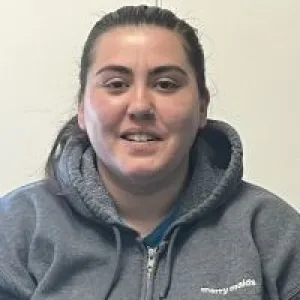 A smiling female Merry Maids ambassador in grey hoodie with dark hair pulled back