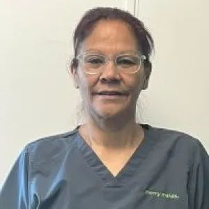 A smiling female Merry Maids ambassador in grey scrubs with dark hair pulled back