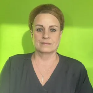 Smiling female in grey scrubs with Merry Maids logo with short blonde hair