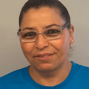 smiling woman with a blue merry maids uniform standing in front of a tan wall