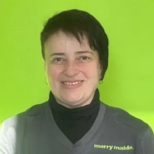 Smiling female in grey scrubs with Merry Maids logo with short dark hair