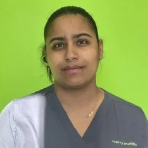 Smiling female in grey scrubs with Merry Maids logo with dark hair tied back