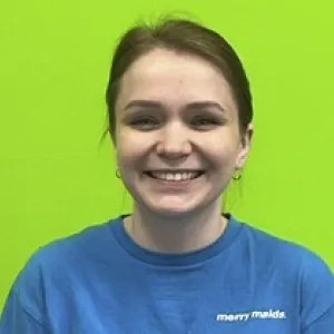 Smiling female in grey scrubs with Merry Maids logo with dark hair tied back