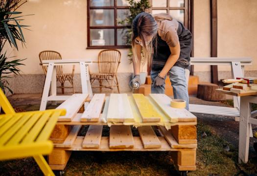 Woman spraying outdoor furniture with a protectant spray to preserve it from the elements. | Merry Maids