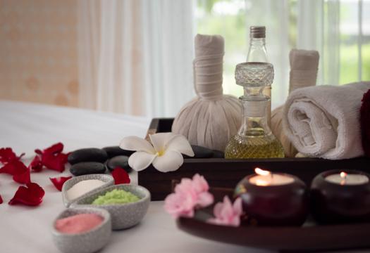 Bath salts and oils sitting nicely on a bed with a tray of towels | Merry Maids