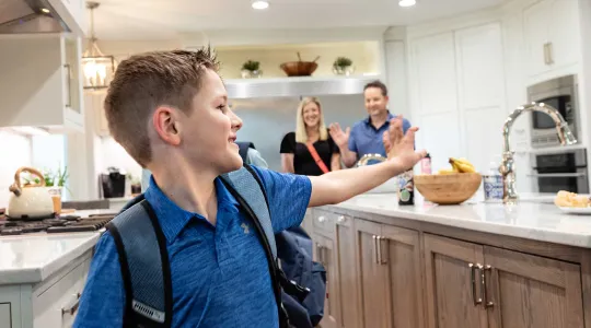 Boy waving to family in kitchen