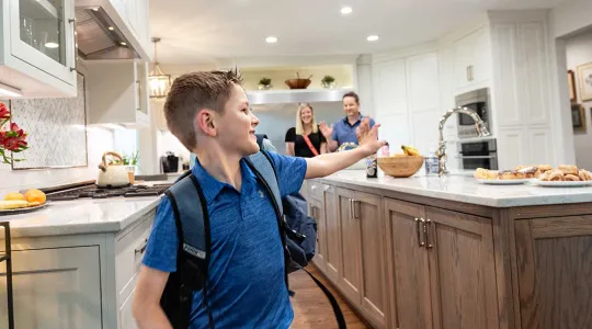 Boy waving to family in kitchen
