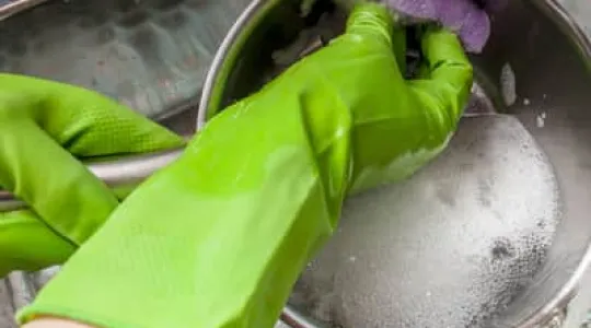 Person cleaning pan with gloves on