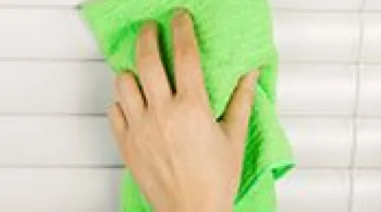 Cleaning blinds with green cloth