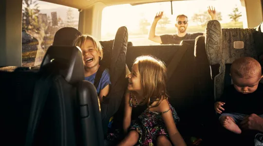Dad Loading Car While Kids Play in Backseat