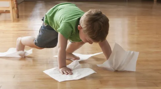 Child cleaning floor with paper towels.