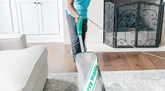 Merry Maids Team Member vacuuming a home.